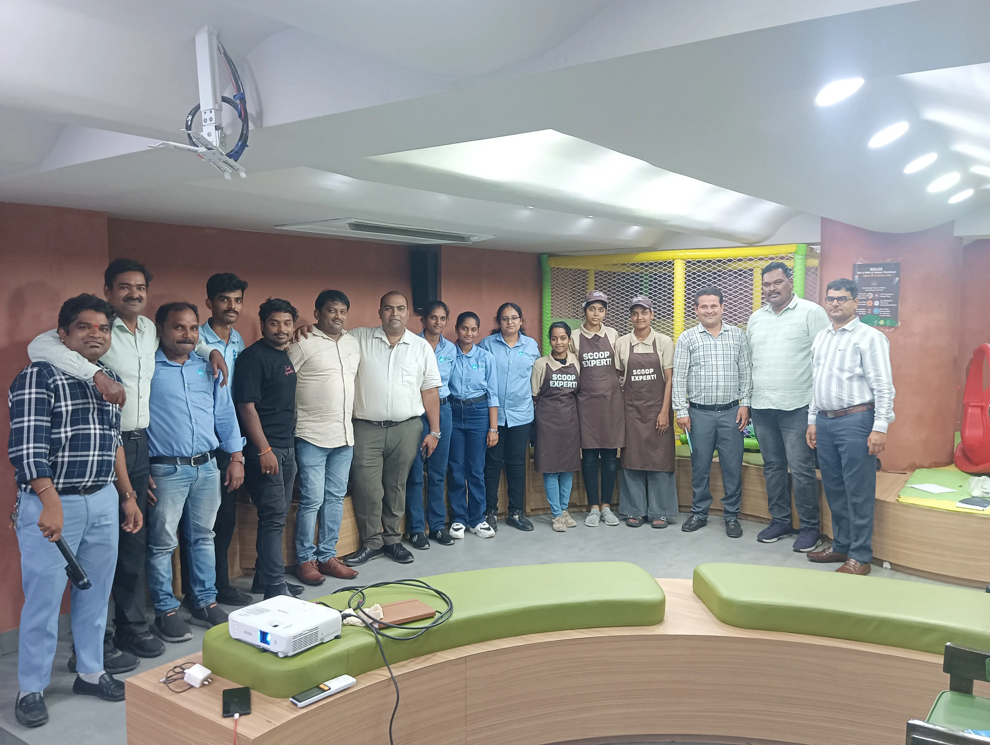 Participants and kitchen staff in aprons standing together in an auditorium after a training session.