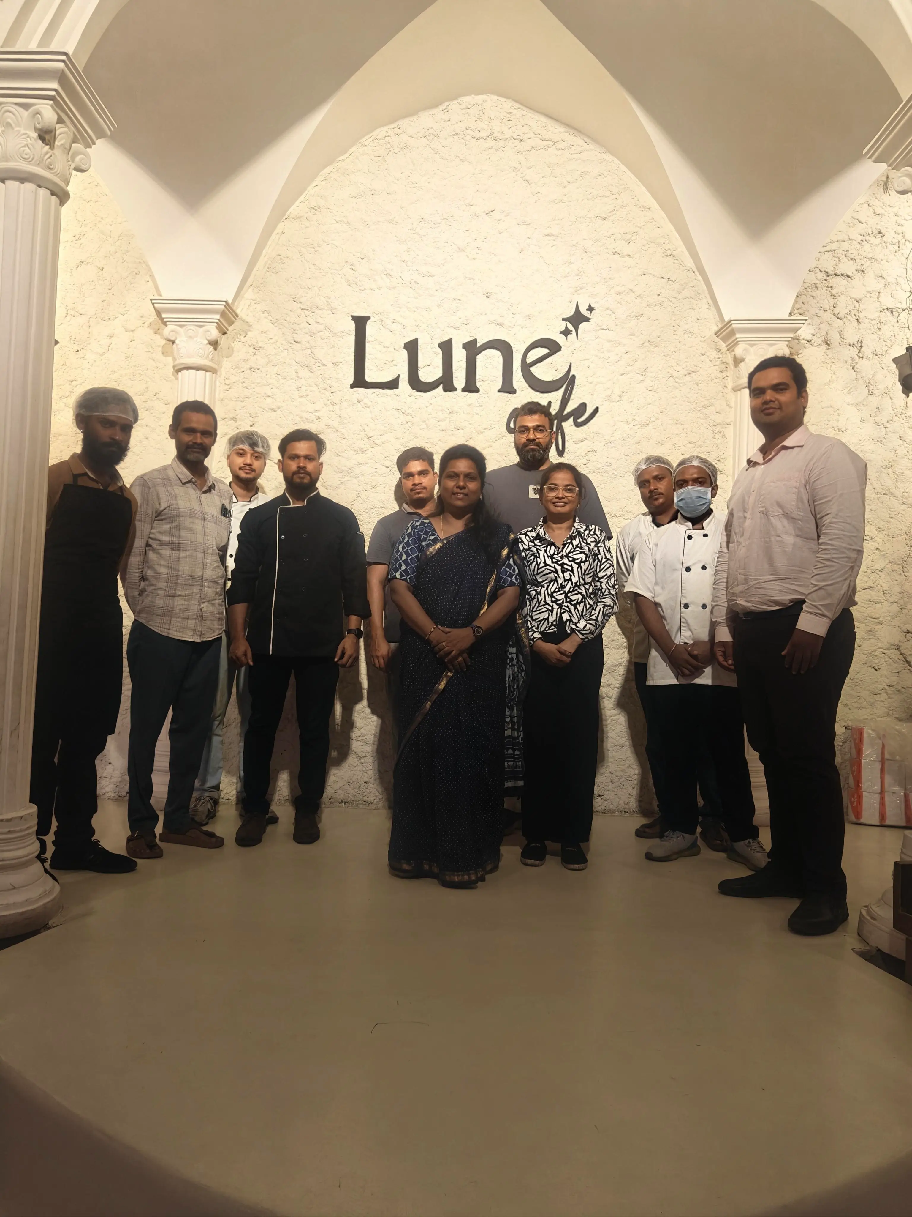 Cafe team standing together for a group photograph inside a modern arched interior.