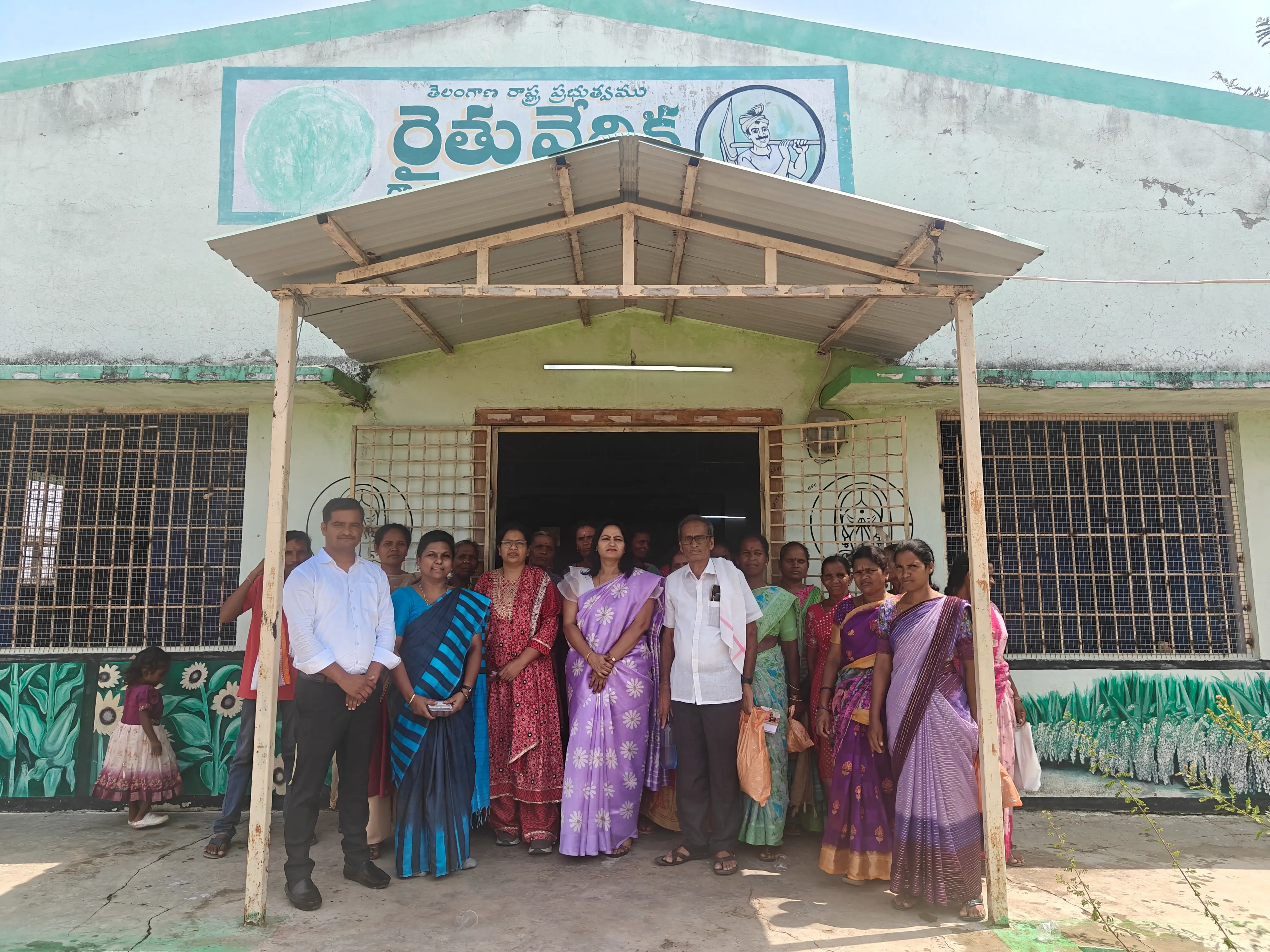 Group photograph of participants standing at the entrance of a rural community building after a programme.