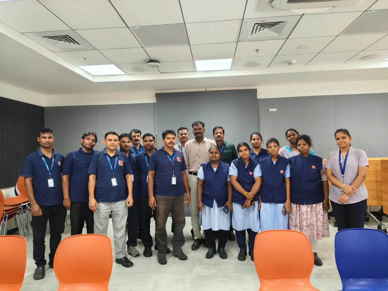 Uniformed staff and trainers standing together in a seminar room following a training programme.