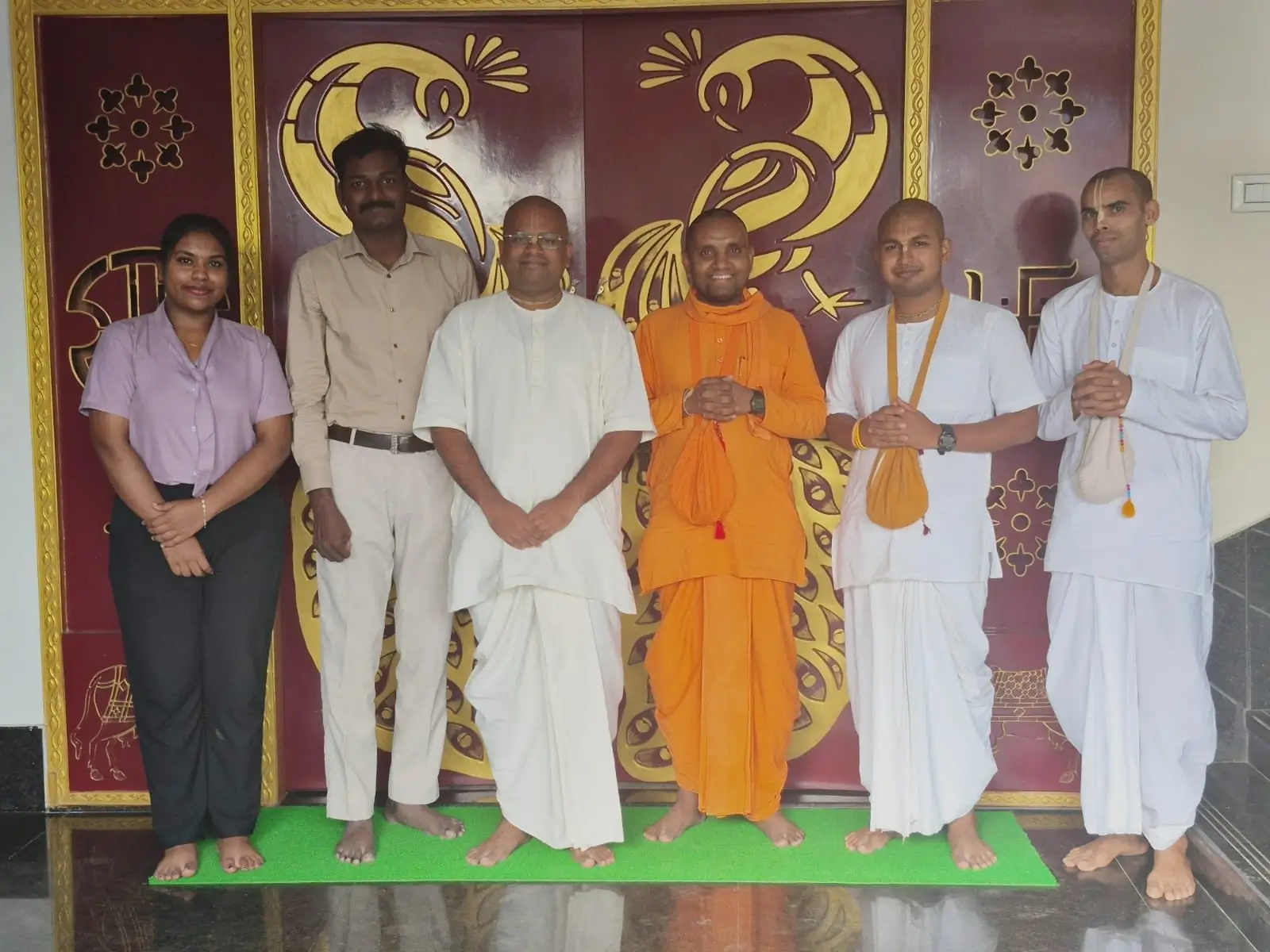 Group of kitchen staff standing together for a photograph in front of a decorated wall.